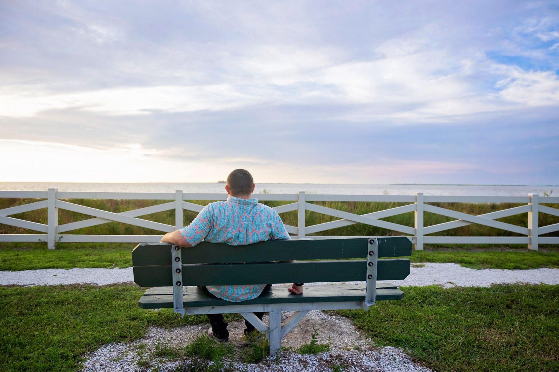 Calming Transformations Counseling - A back view of Chad Thompson sitting on a chair while looking a the sunset at the beach - counseling and telehealth therapy