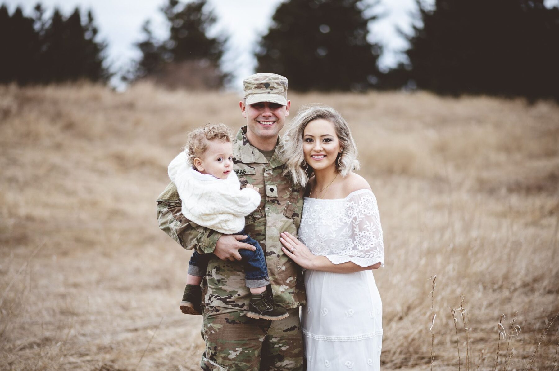 Calming Transformations Counseling - A family of three where the father is in military uniform standing in an open space with trees - therapy for military families