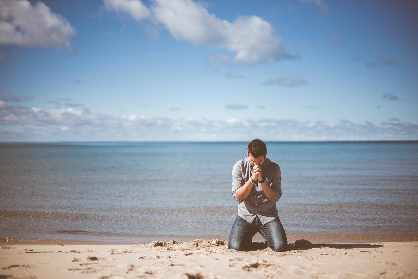 Calming Transformations Counseling - a man kneeling and praying on a sandy beach - Christian counseling